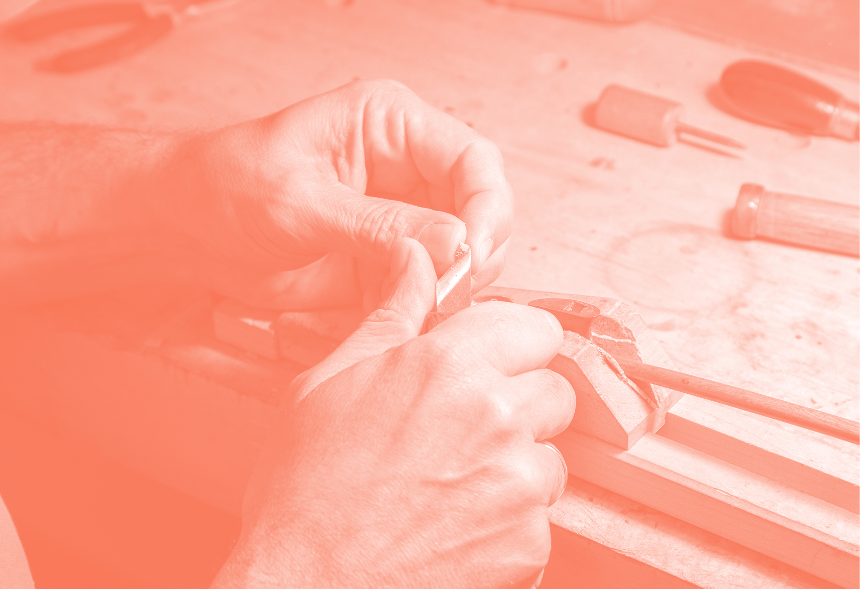 Artisanal fabric processing: hands carving wood in the foreground