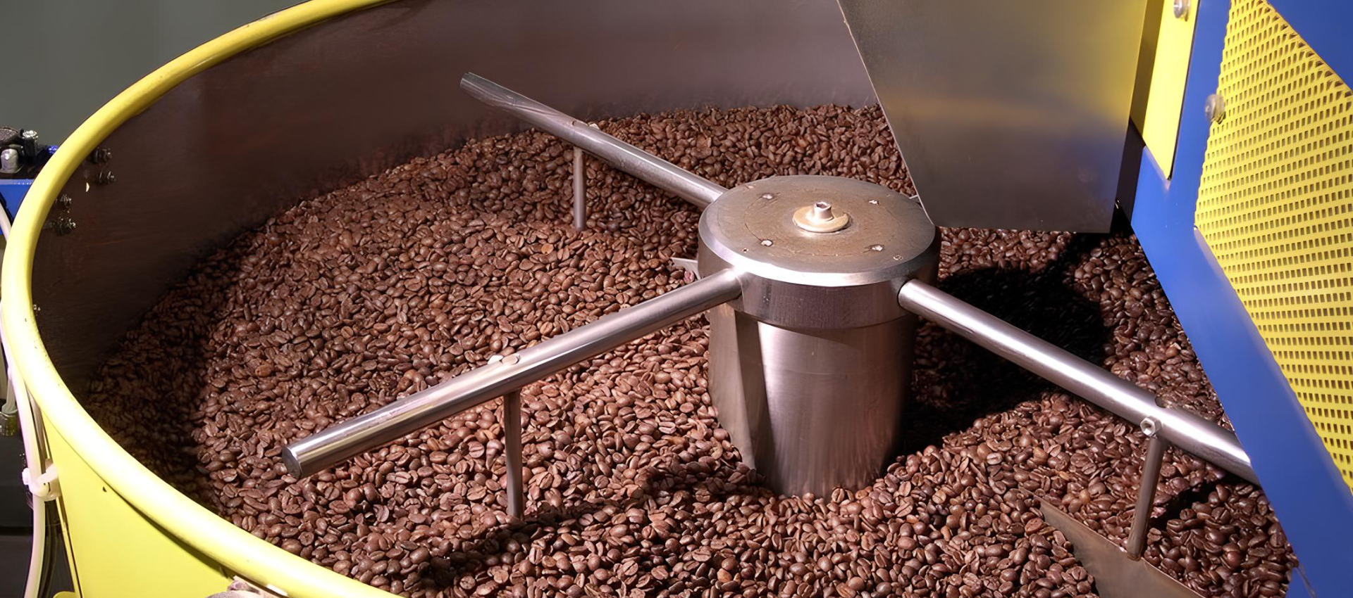 Chicchi di caffè tostati in una tostatrice professionale.