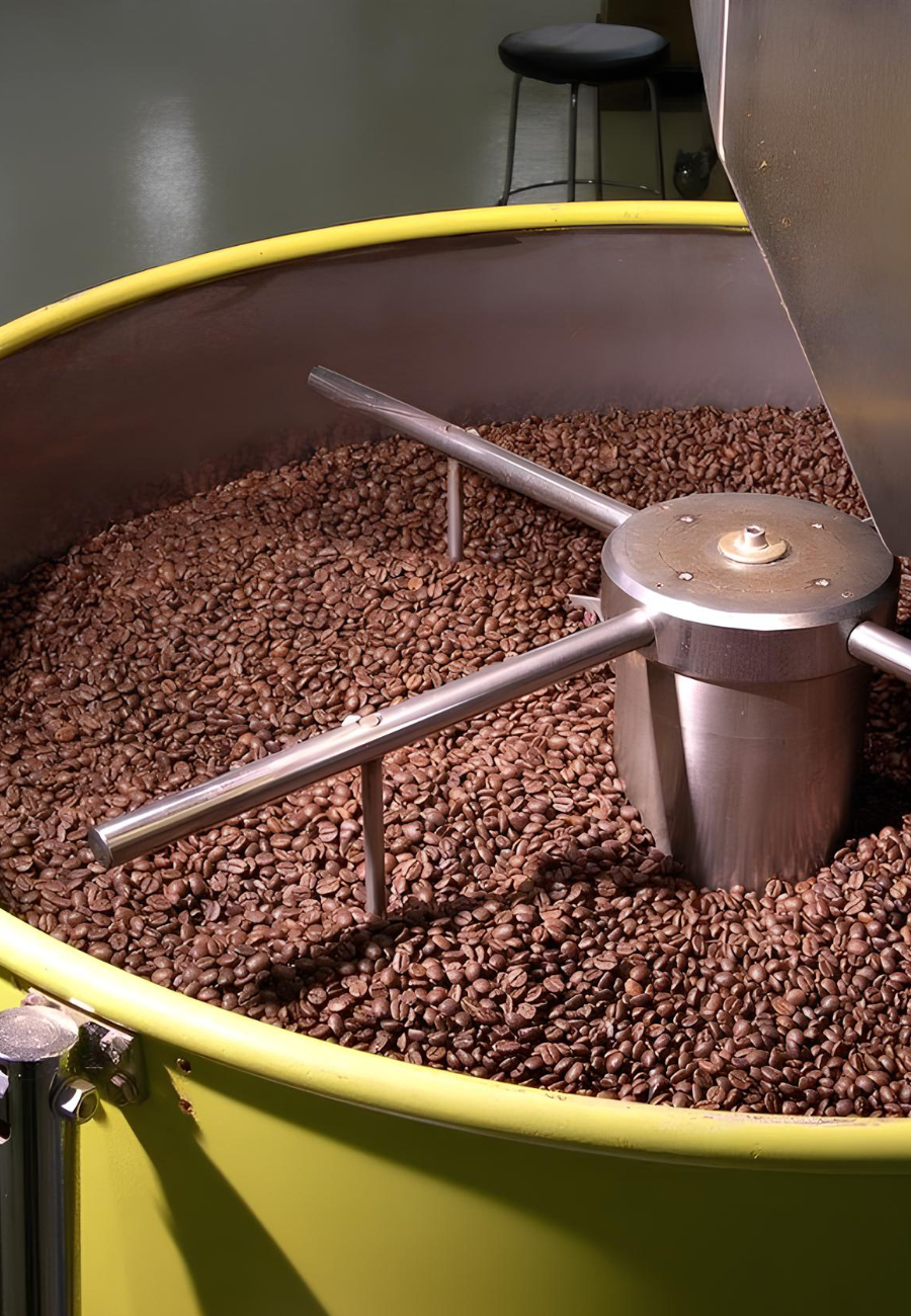 Chicchi di caffè tostati in una tostatrice professionale.